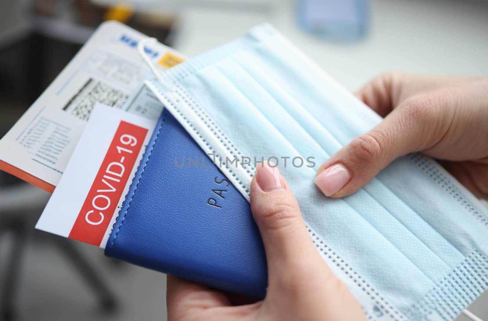 Female hand holding covid-19 vaccination passport and plane tickets closeup. Traveling abroad during coronavirus pandemic concept