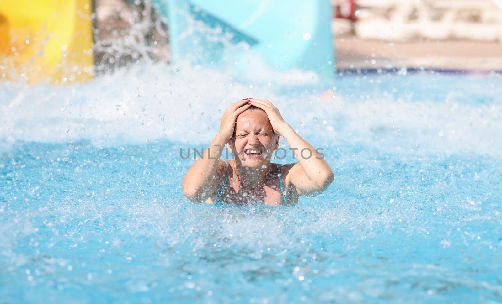 Portrait of woman who has driven down slide in water park. Fun in the water park for adults concept