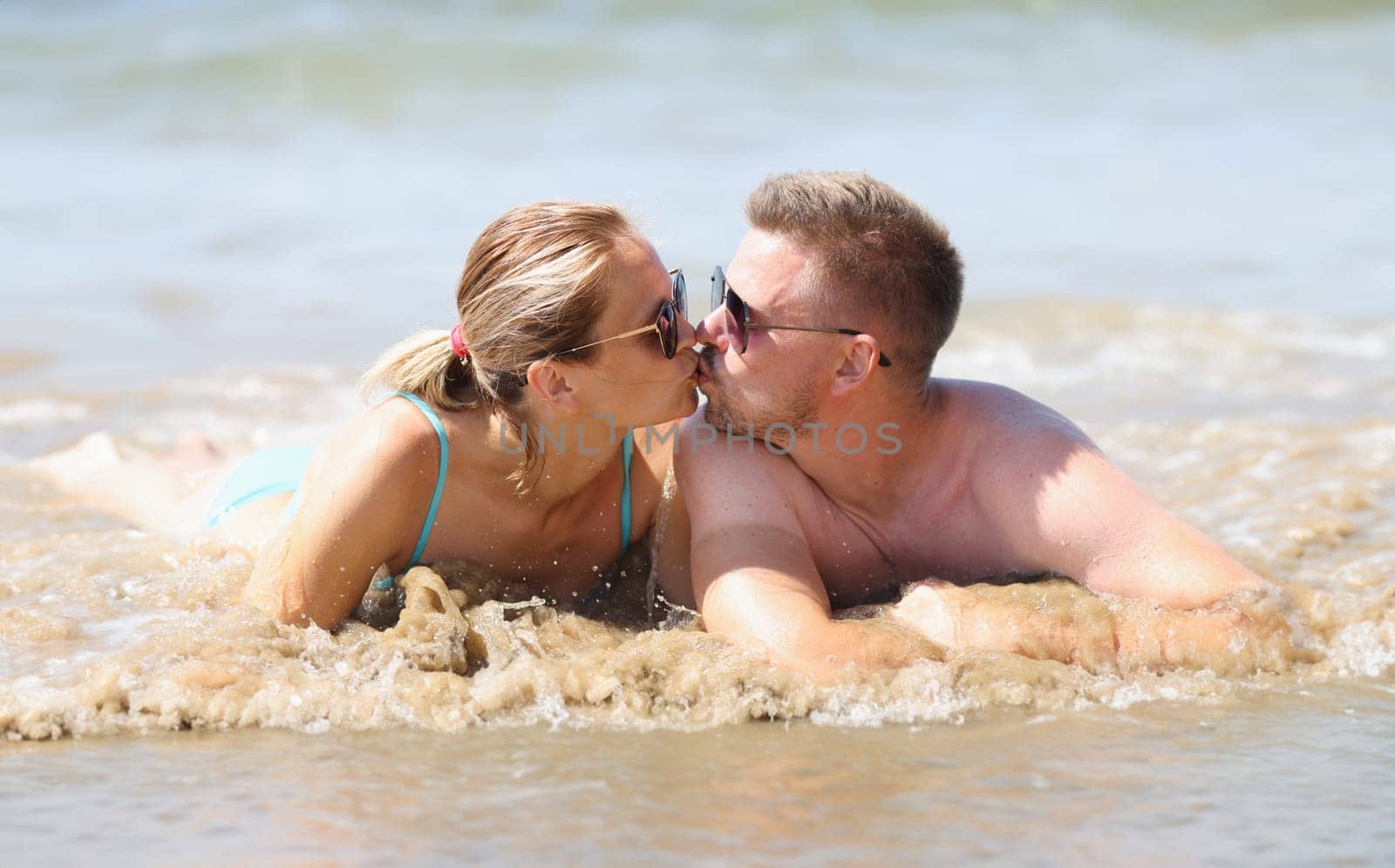 Man and woman are lying on beach and kissing. Holiday romance concept