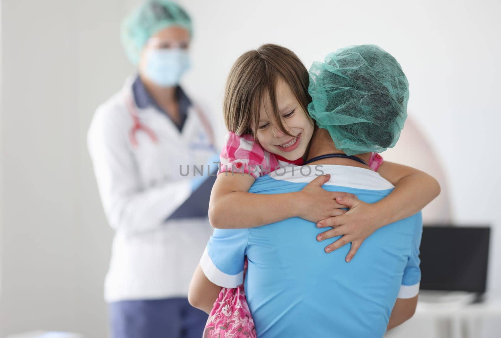 Doctor is holding little girl in his arms. by kuprevich