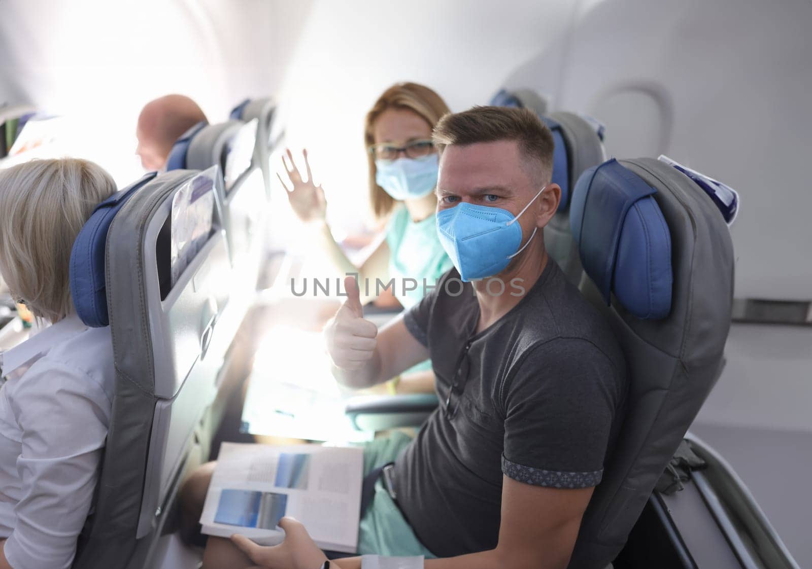 Man and woman in medical protective masks on plane. Safe flying in coronavirus pandemic concept