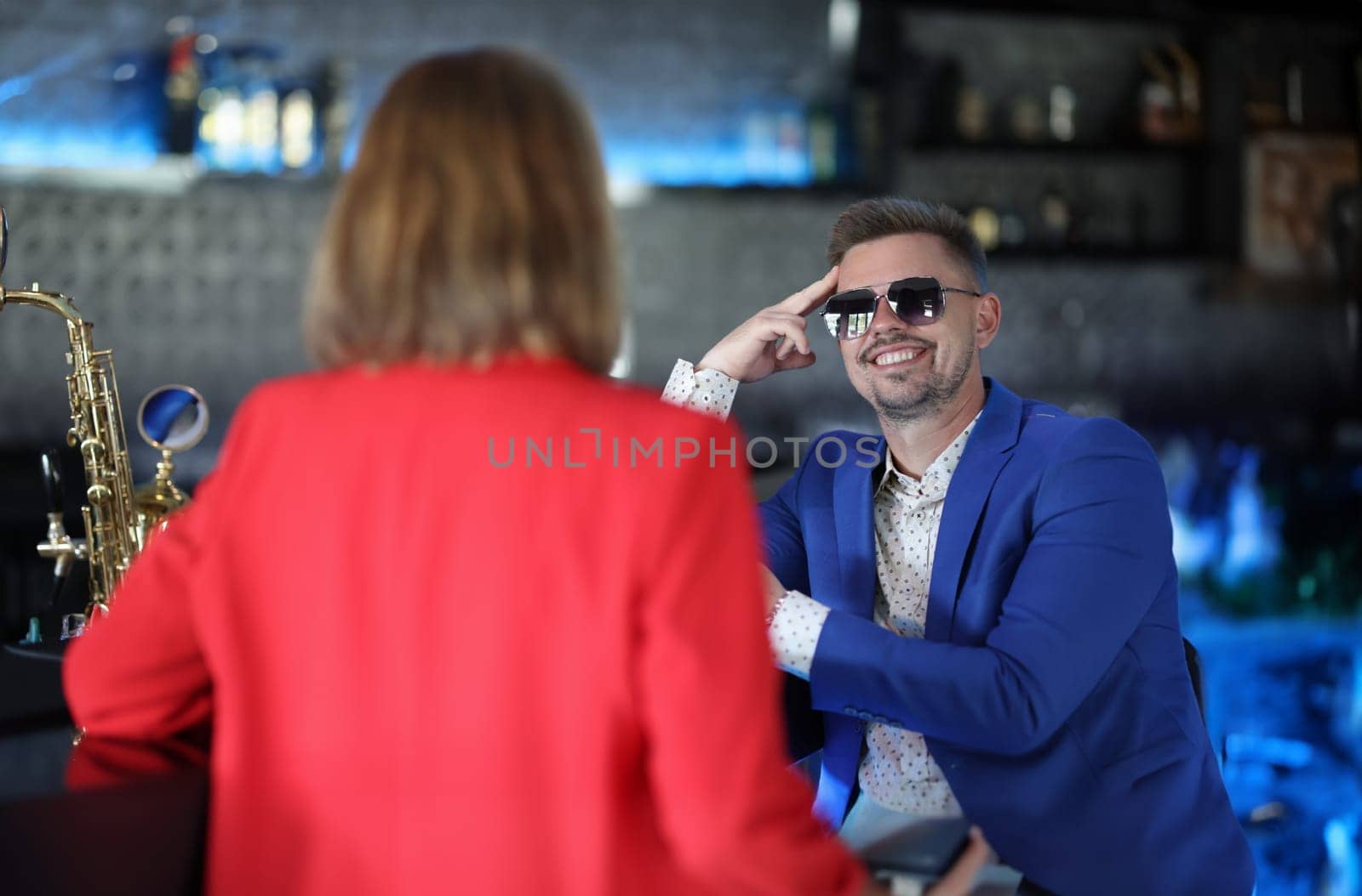 Smiling confident man in sunglasses meets woman near bar counter. Narcissistic personality disorder in men concept