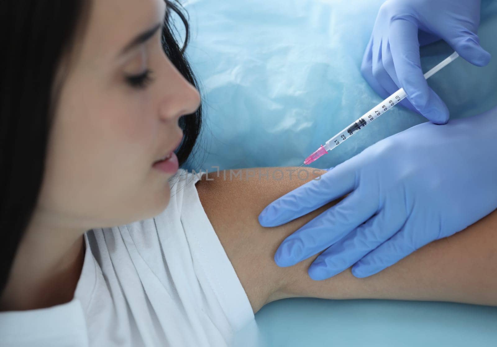 Doctor gives woman an injection in shoulder. New vaccine development and volunteer trials concept