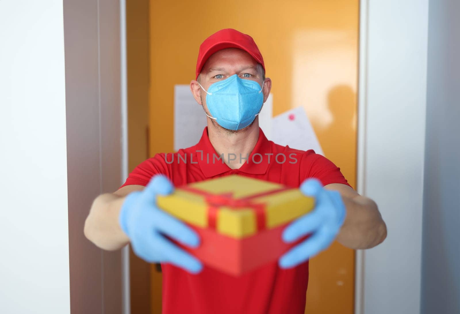 Courier wearing medical protective mask brought box with protective gloves. Delivery of parcels to coronavirus pandemic concept