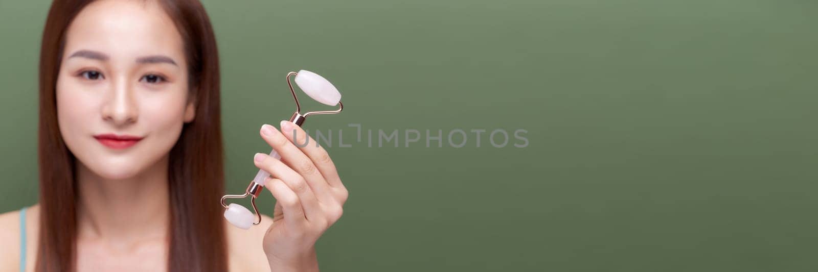 Panorama of girl uses beauty gua sha jade quartz roller. 