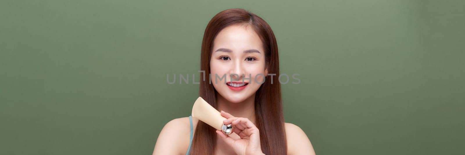 Beautiful asian woman face portrait holding and presenting cream tube product on banner. by makidotvn