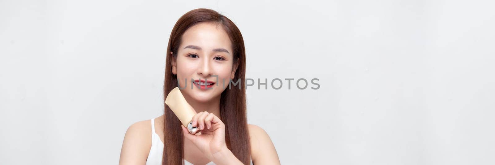 Smiling young beauty asian woman showing skincare products isolated on banner background. by makidotvn