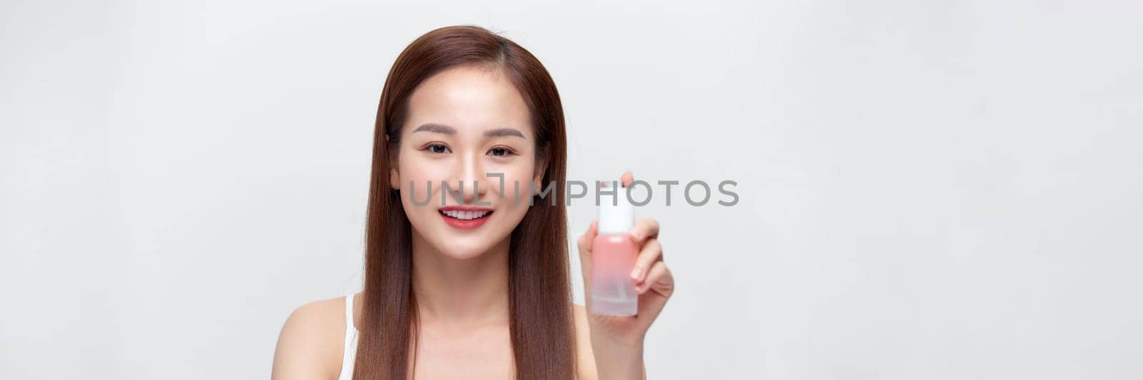 Smiling young beauty asian woman showing skincare products isolated on banner background.