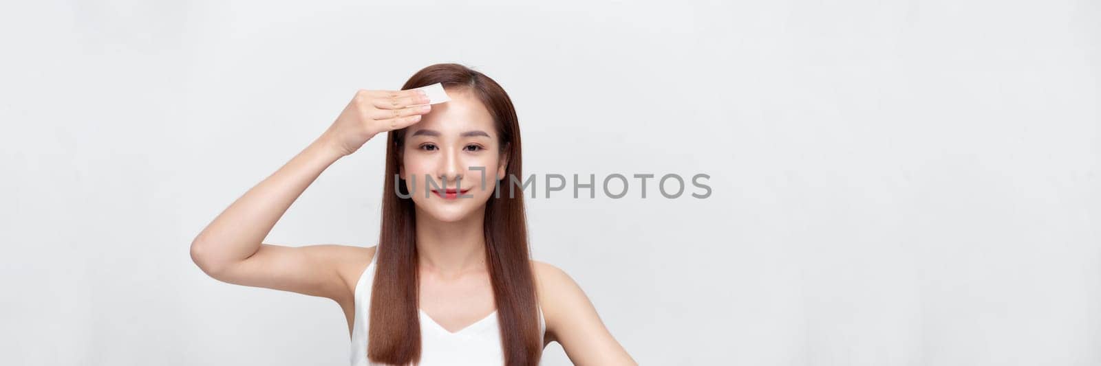 beautiful happy asian girl model with natural makeup using oil absorbing sheets. panorama. by makidotvn