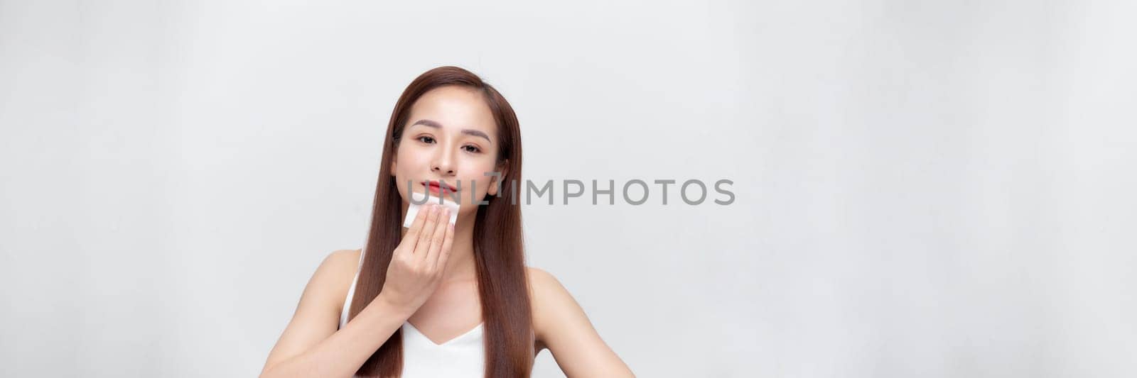 Panorama with woman removing oil from face using blotting papers. 