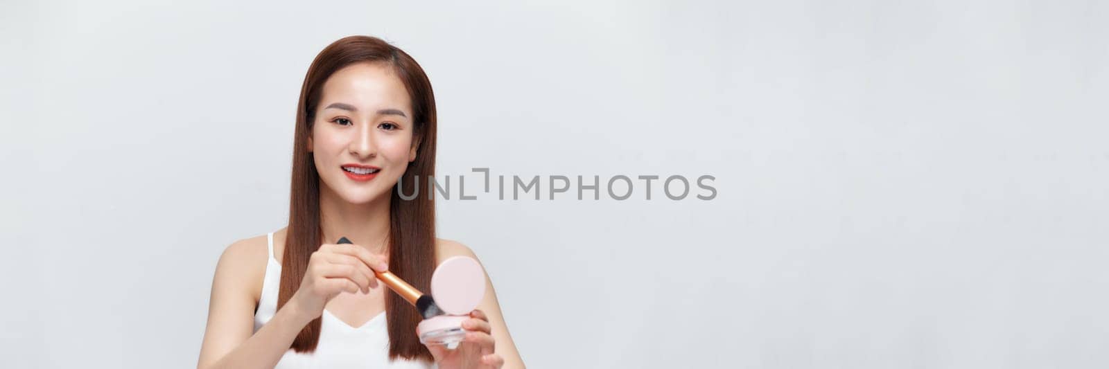 Glamorous beautiful female applying cushion powder for facial makeup concept on banner by makidotvn