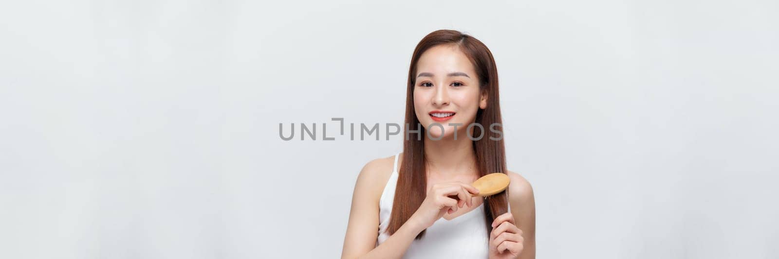 Pretty asian woman is combing her hair isolated on the white background. panorama