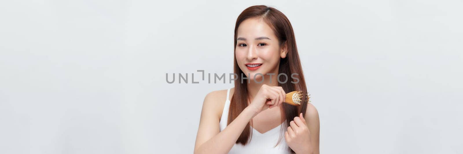 Pretty asian woman is combing her hair isolated on the white background. panorama by makidotvn