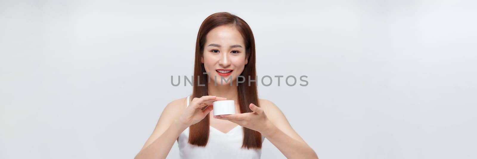 Attractive beautiful woman holding cosmetic jar applying make up on white banner by makidotvn