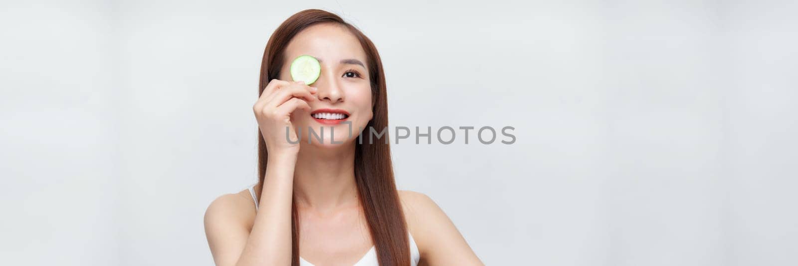 Young beautiful woman with cucumber slices on white background, panorama