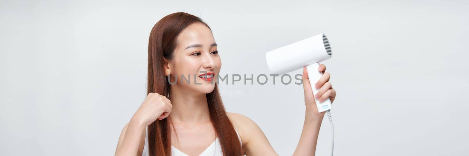 portrait of a young woman using a dryer on white banner background
