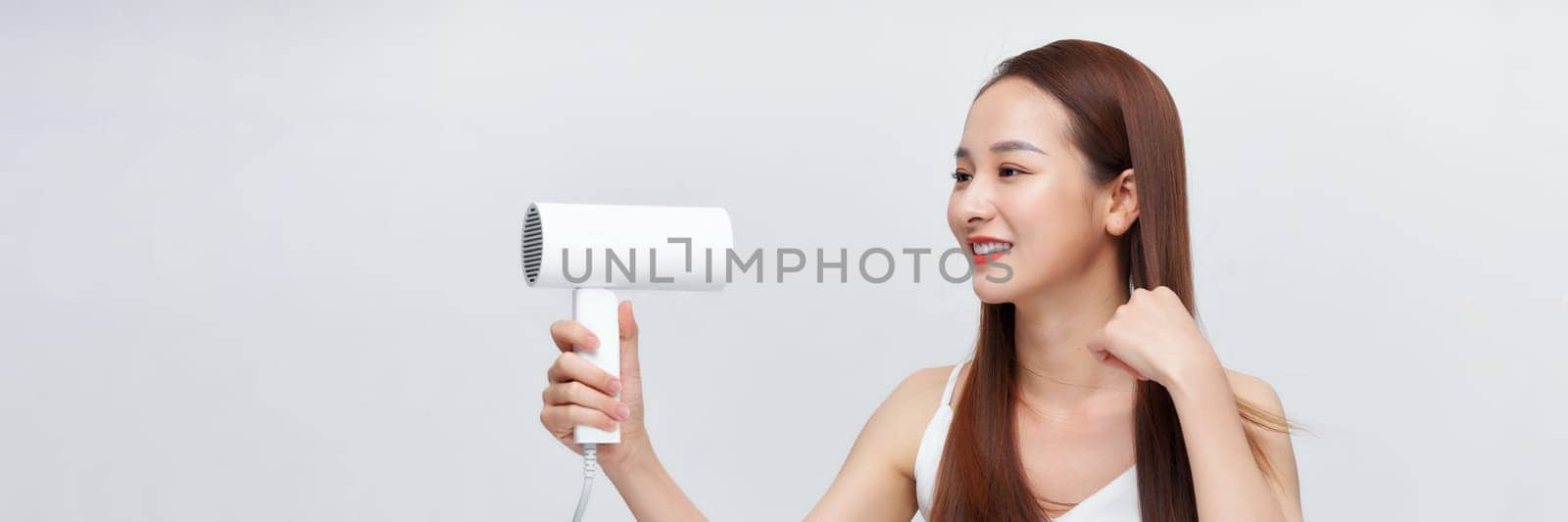 Banner of beautiful smiling girl with long straight hair using hairdryer.  by makidotvn