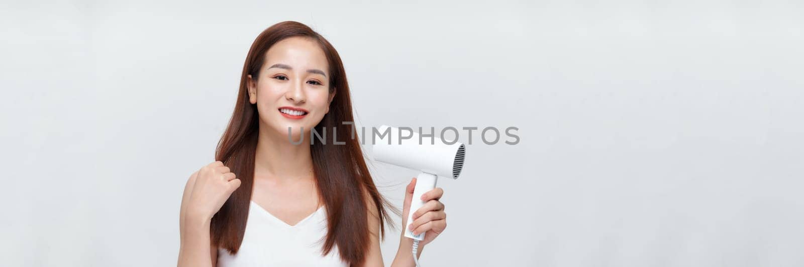 Banner of beautiful smiling girl with long straight hair using hairdryer. 