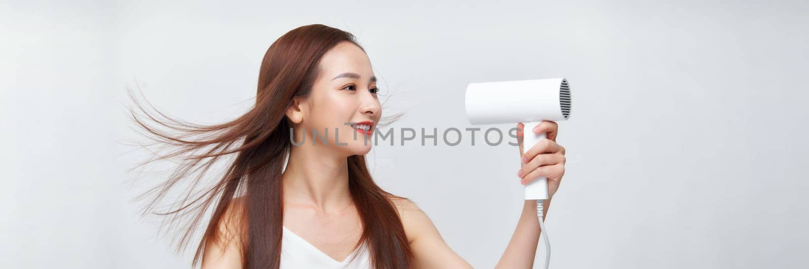 portrait of a young woman using a dryer on white banner background