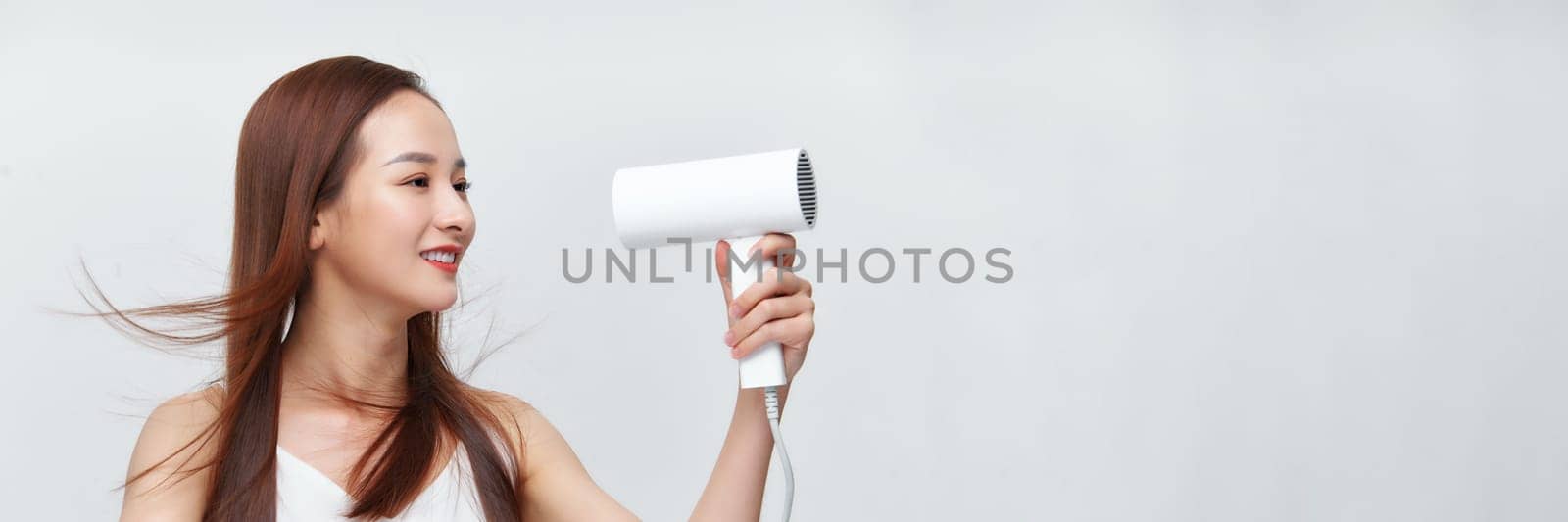 Banner of young asian woman using hair dryer on white background
 by makidotvn