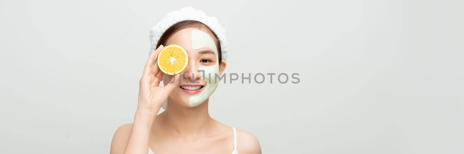 Smiling woman with orange slice and mud mask on face for web banner by makidotvn