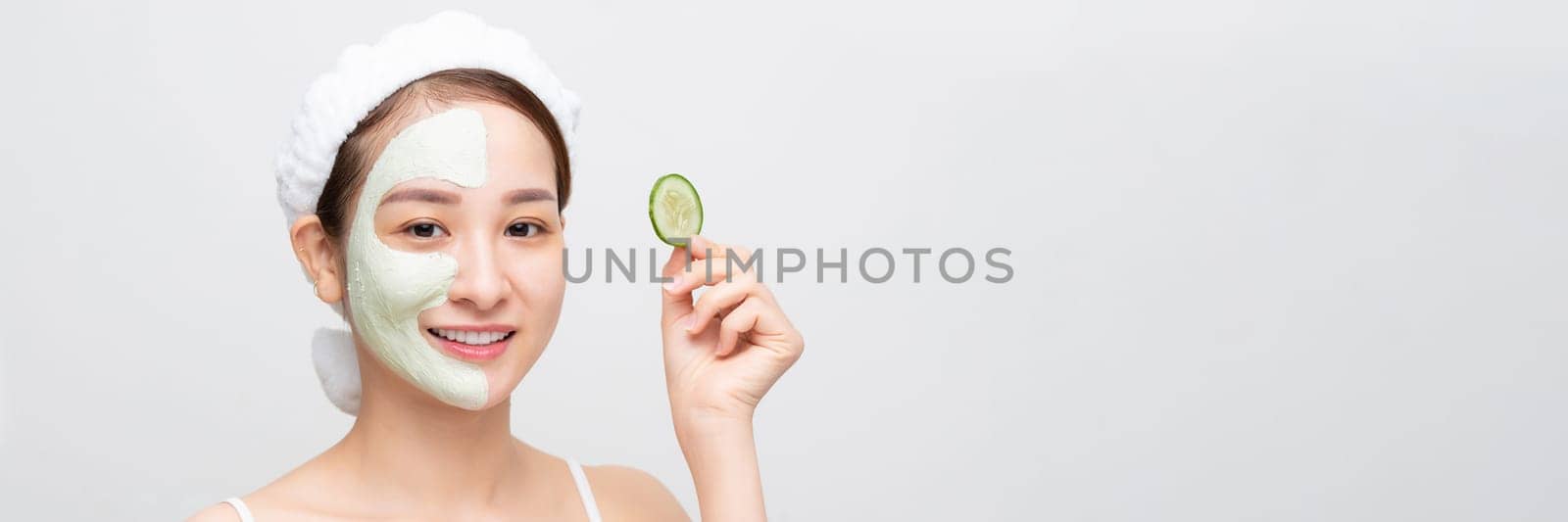 Beautiful girl holding a slice of cucumber in front of her face.  by makidotvn