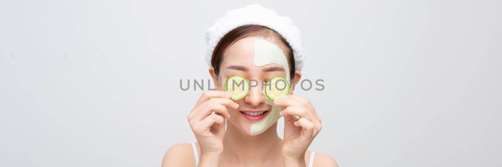 naked young woman with clay mask and cucumbers on face isolated on wide banner