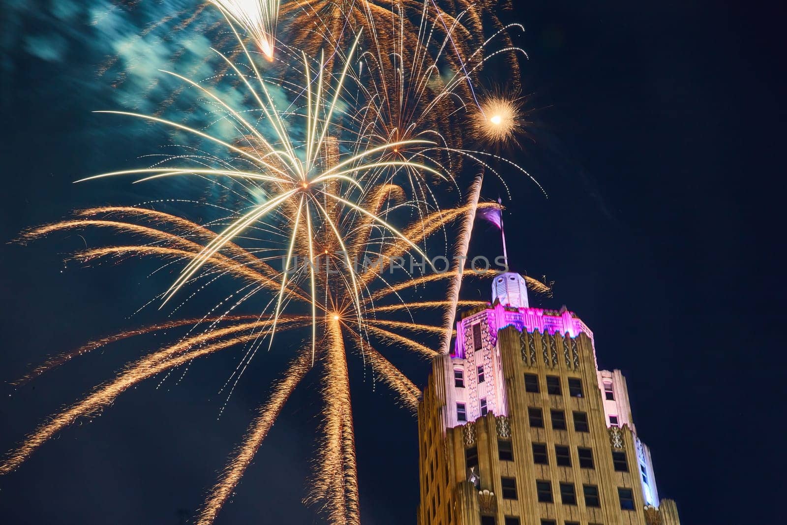Image of Gold fireworks behind Lincoln Tower downtown Fort Wayne on 4th of July with purple lights