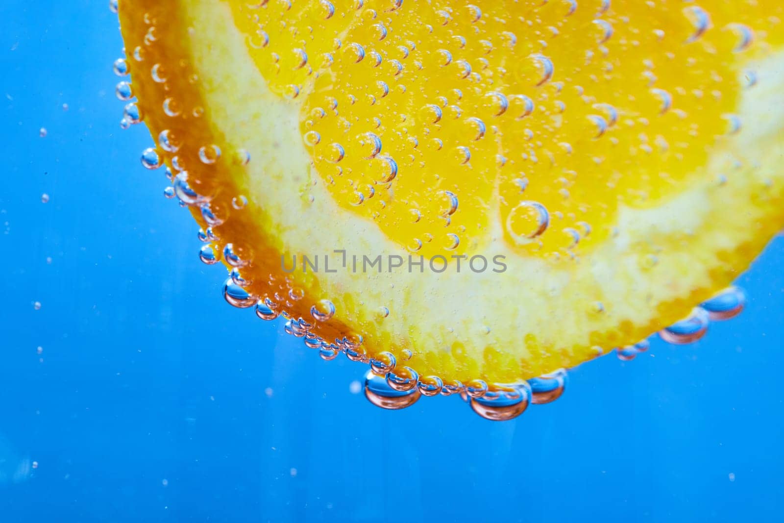 Image of Edge of orange slice covered in silvery bubbles with blue background