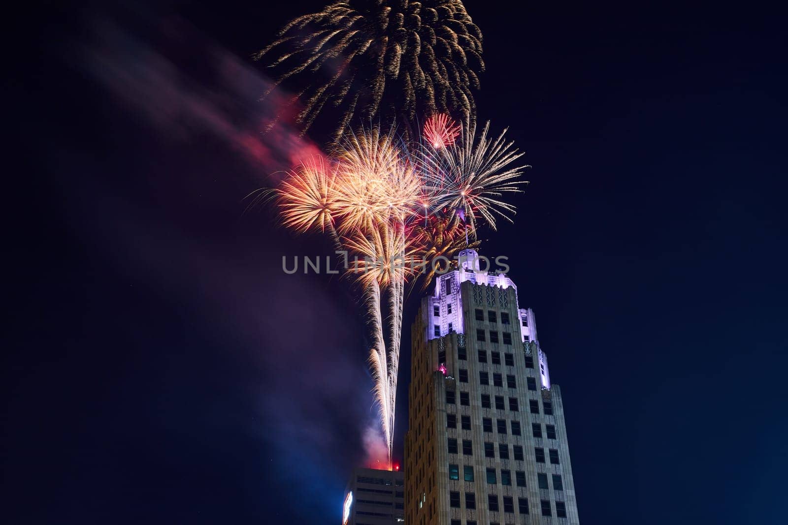 Image of Close up of fireworks launching from Indiana Michigan Power building and purple top of Lincoln Tower
