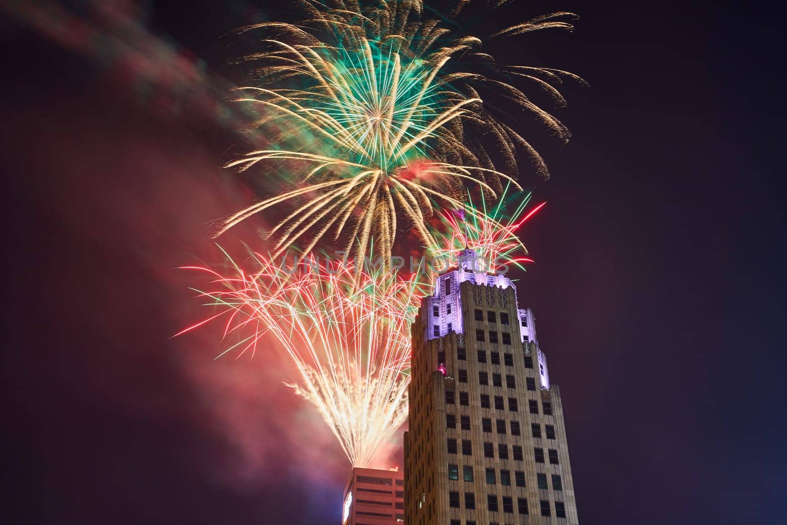 Image of Top of purple Lincoln Tower with dazzling Fourth of July fireworks display in Fort Wayne