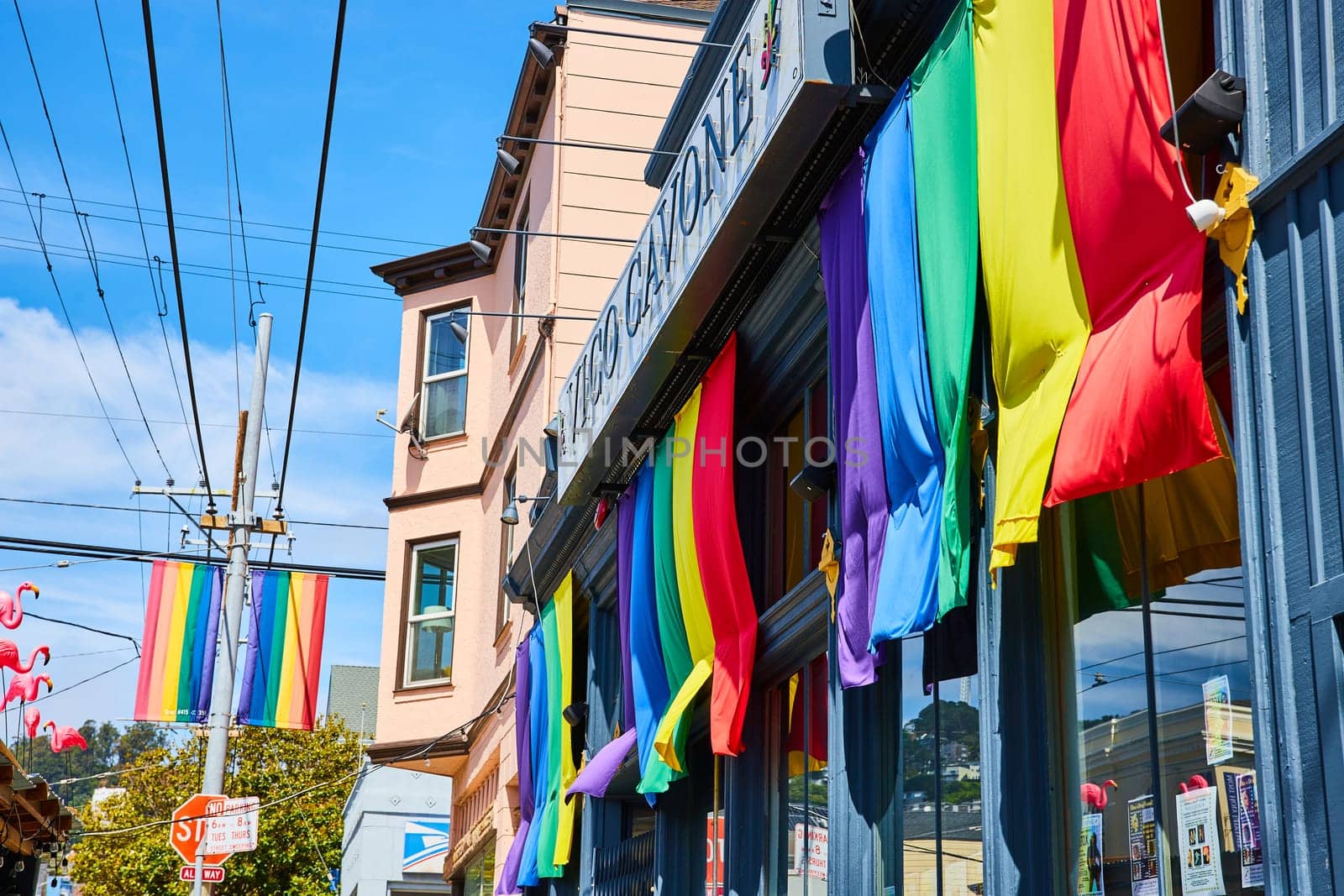 Image of Rainbow banners on Vico Cavone building with blue sky in San Francisco California