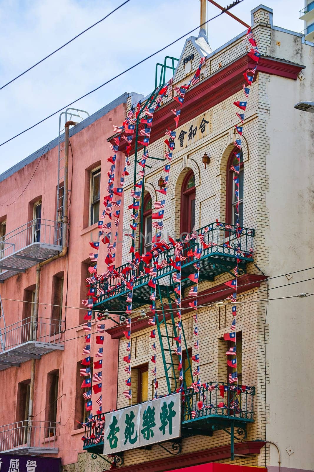 Image of Fire escape covered in string of American and Chinese flags on white brick building
