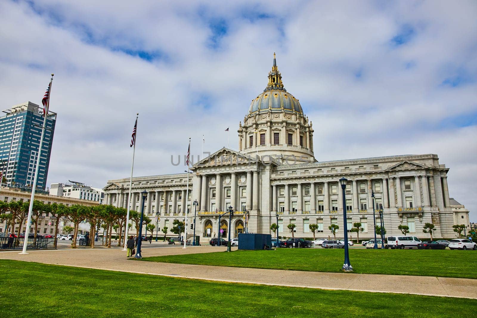 Image of San Francisco city hall with pedestrians on sidewalk and cloudy blue sky overhead