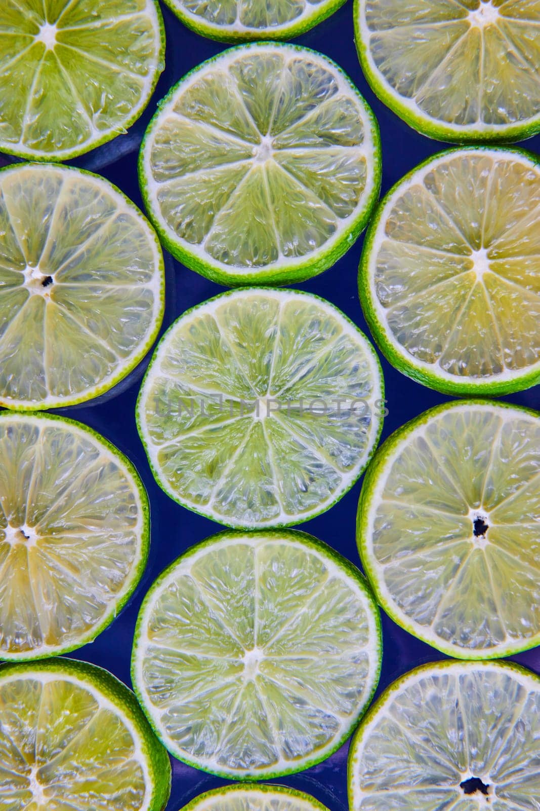Image of Bright and see through green lime slices on navy blue background