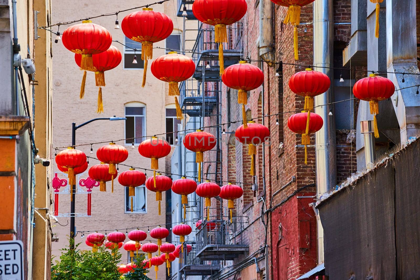 Image of Strings of Chinese paper lanterns hanging from wires attached to buildings and fire escapes