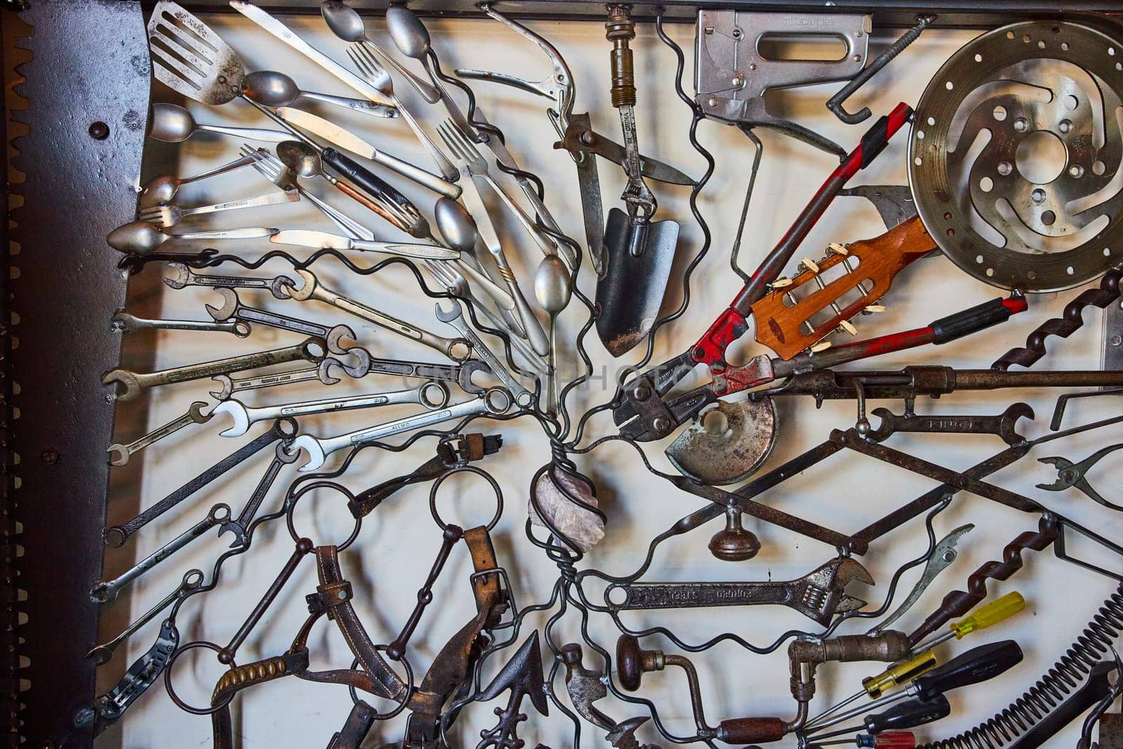 Image of Wall of interconnecting tools and assorted metal objects connected by wires with white background