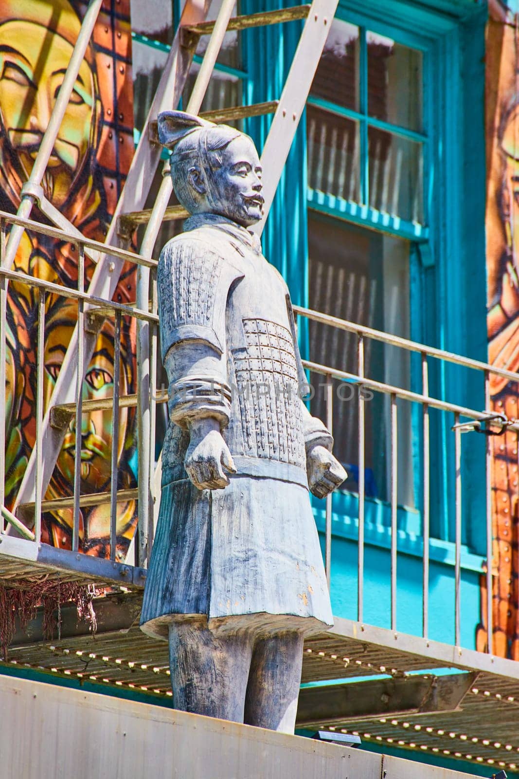 Image of Side view of Chinese man statue standing in front of soldier mural