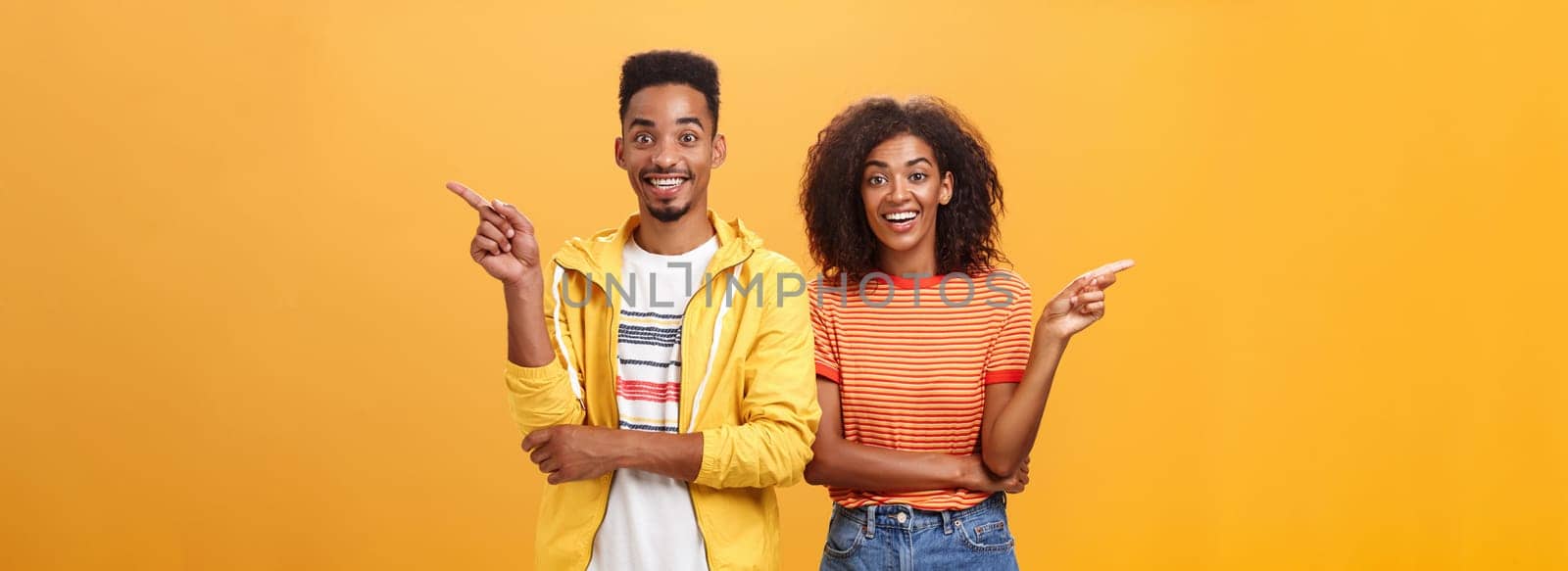 Which one telling true. Joyful and friendly good-looking couple, african american woman pointing left and dark-skinned guy right smiling broadly at camera giving advices but disagree with each other.