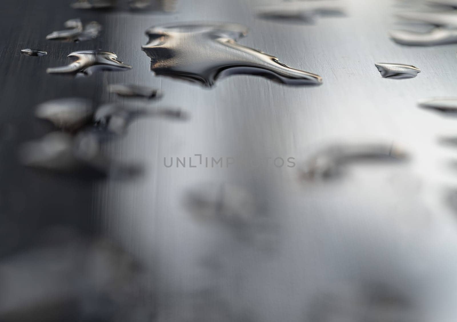 Detail of Water droplets caused by rain perched on the metallic surface. Rain water drops on a stainless steel handle, Natural Pattern of dew drops or raindrops on silver metal background for wallpaper poster and banner design, Selective focus.