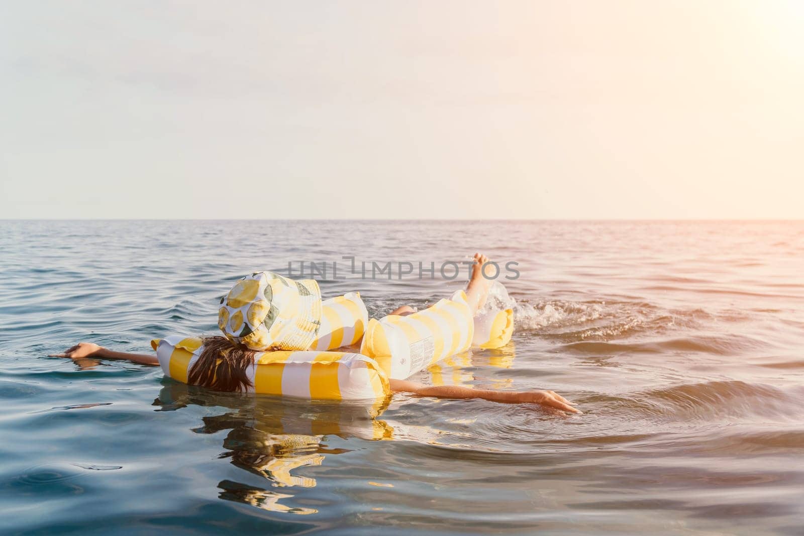 A person floats on a yellow and white inflatable raft in a calm sea.