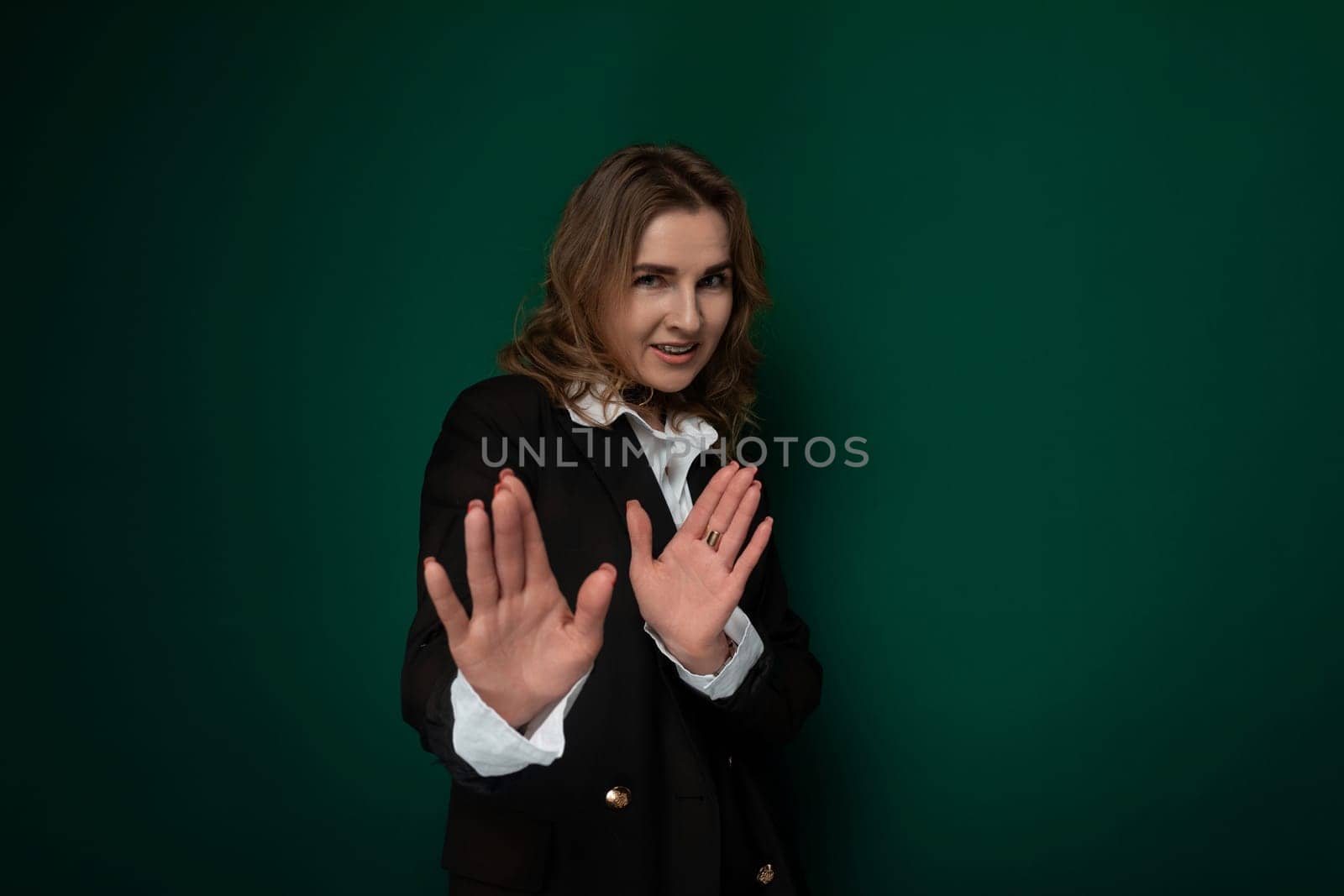 A woman wearing a black jacket stands with her hands outstretched in front of her. She appears to be reaching or gesturing towards something in the distance.