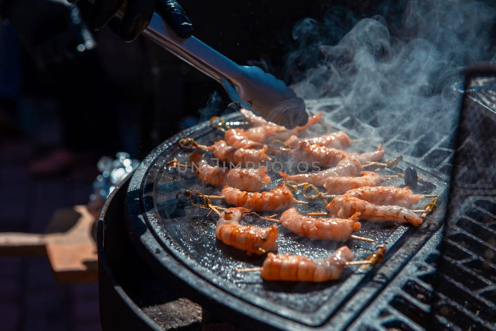 A professional cook prepares shrimps on the grill outdoor, food or catering concept