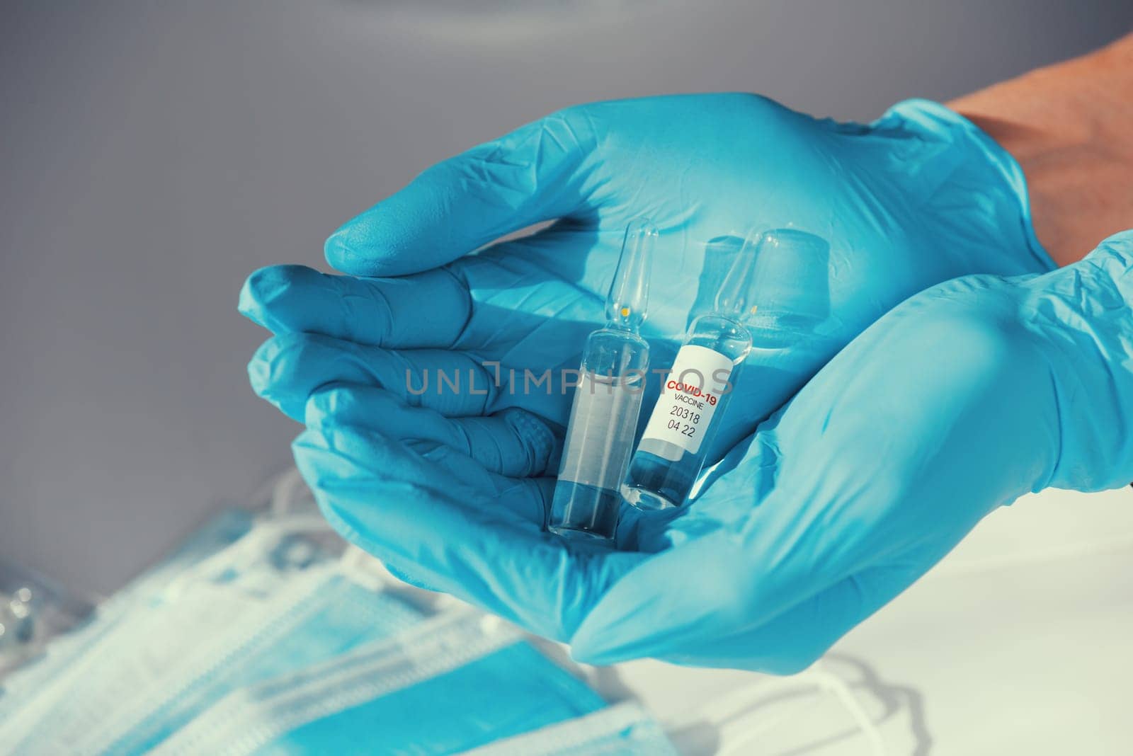 Coronavirus vaccine concept: covid-19 vaccine in hand with blue protective gloves.