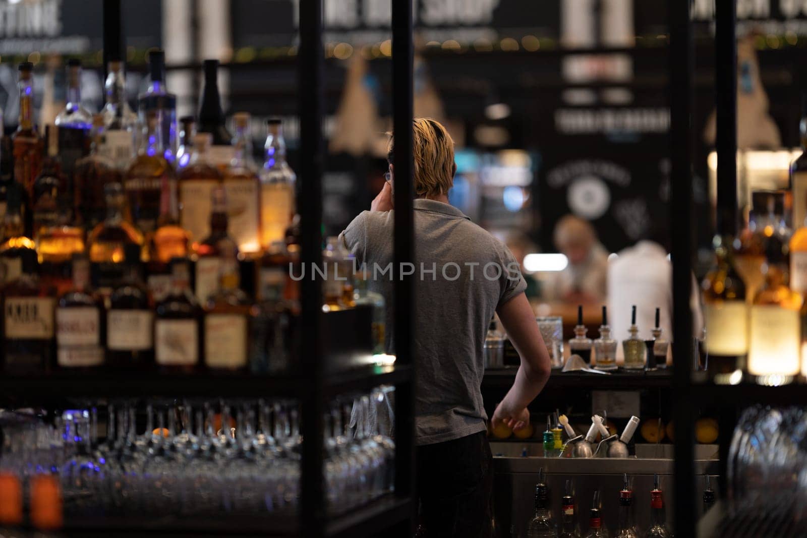 Bartender works in the bar at the restaurant - view from the back. Mid shot