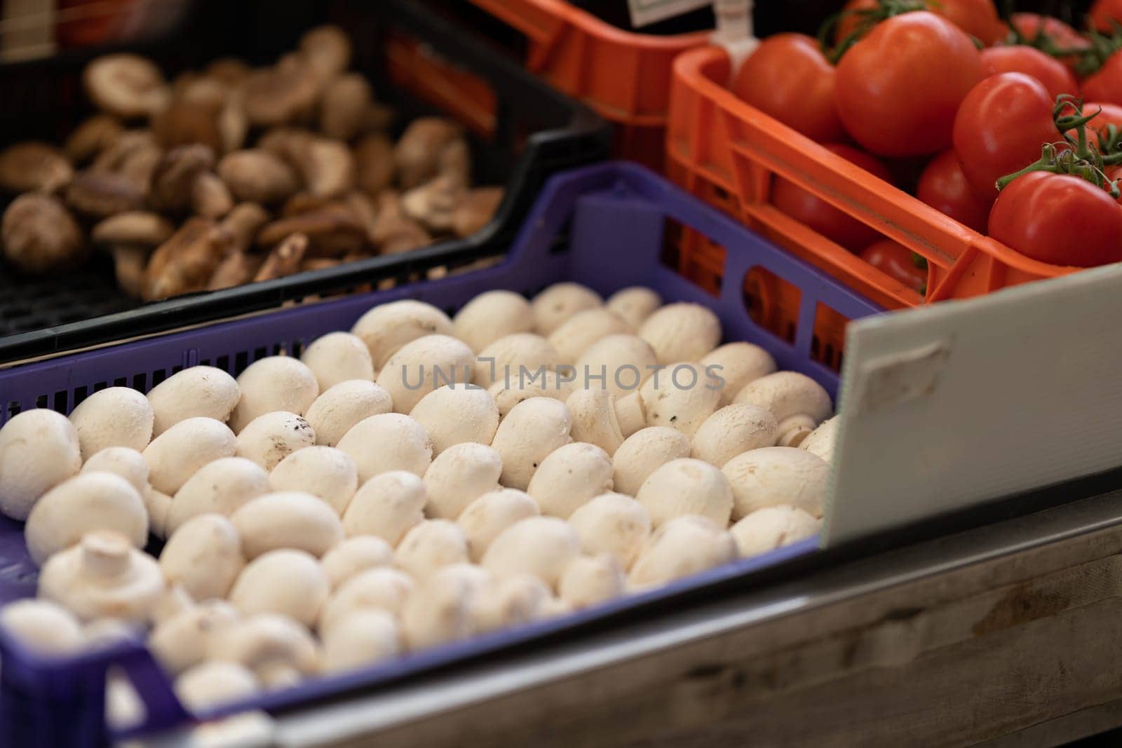 Mushrooms and tomatoes in plastic containers on the market. Mid shot