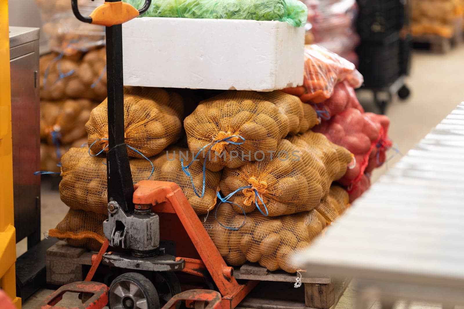 Killograms of potatoes in mesh bags on a trolley at the market. Mid shot