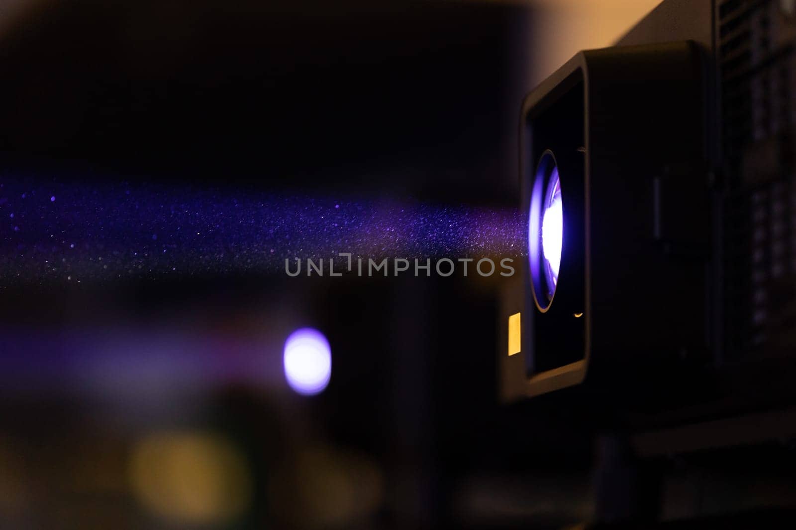 Light coming from the cinema spotlight broadcasting the presentation. Mid shot