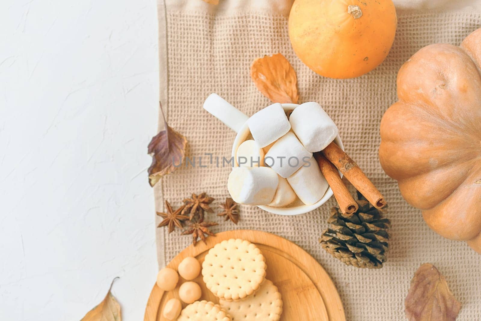 Rustic autumn still life featuring marshmallows, cookies, pumpkins, cinnamon sticks, and fall decorations.