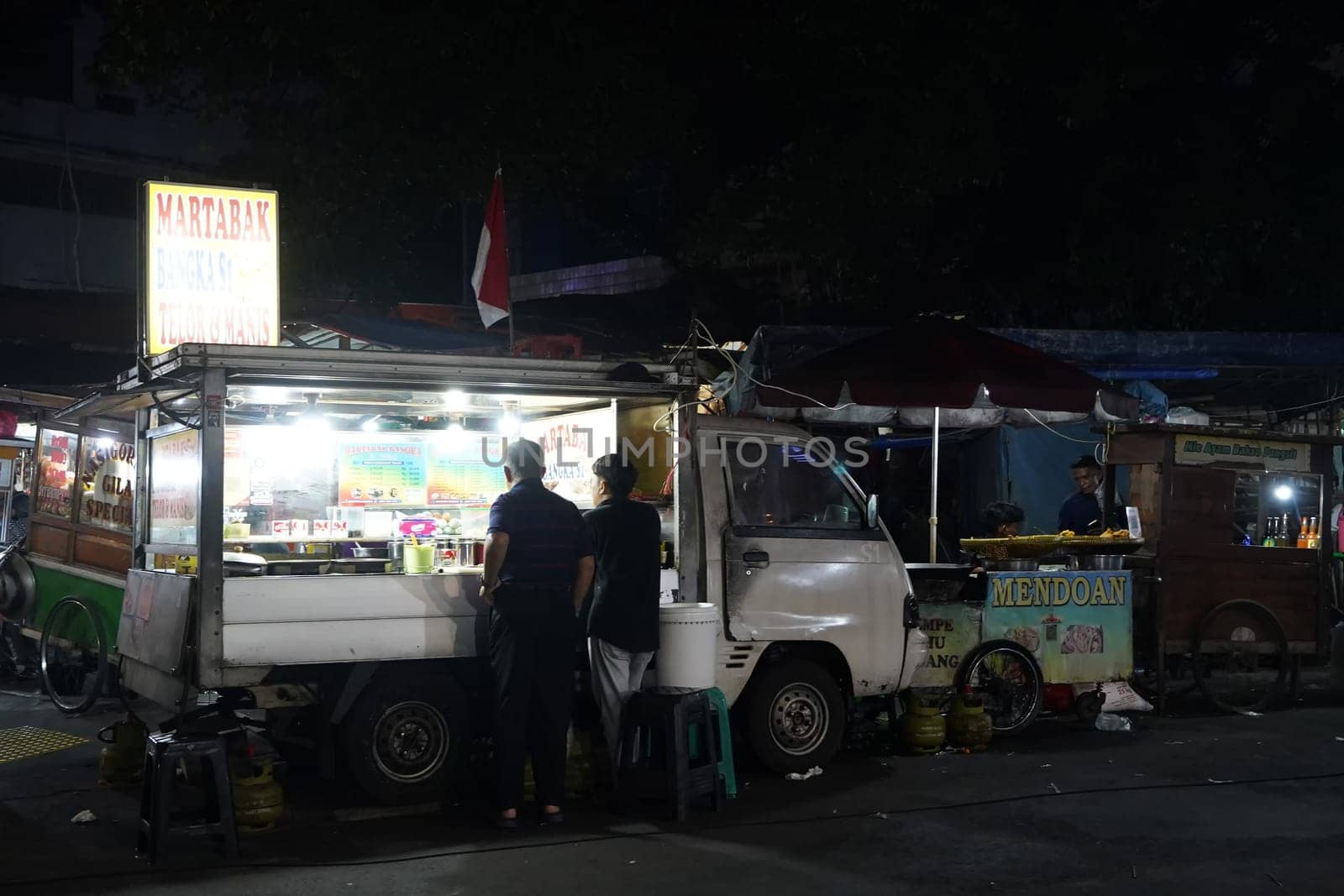 August 14, 2024. Jakarta, Indonesia. A bustling night scene in a corner of the city, filled with street vendors and shoppers.